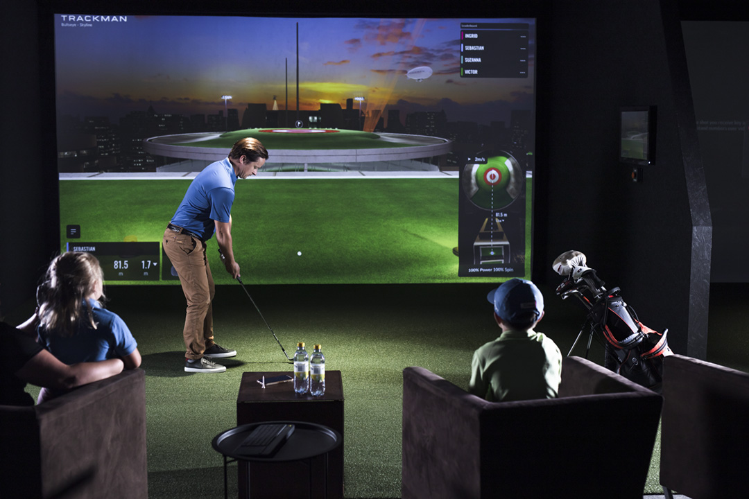 A coach working with a player at a TrackMan bay